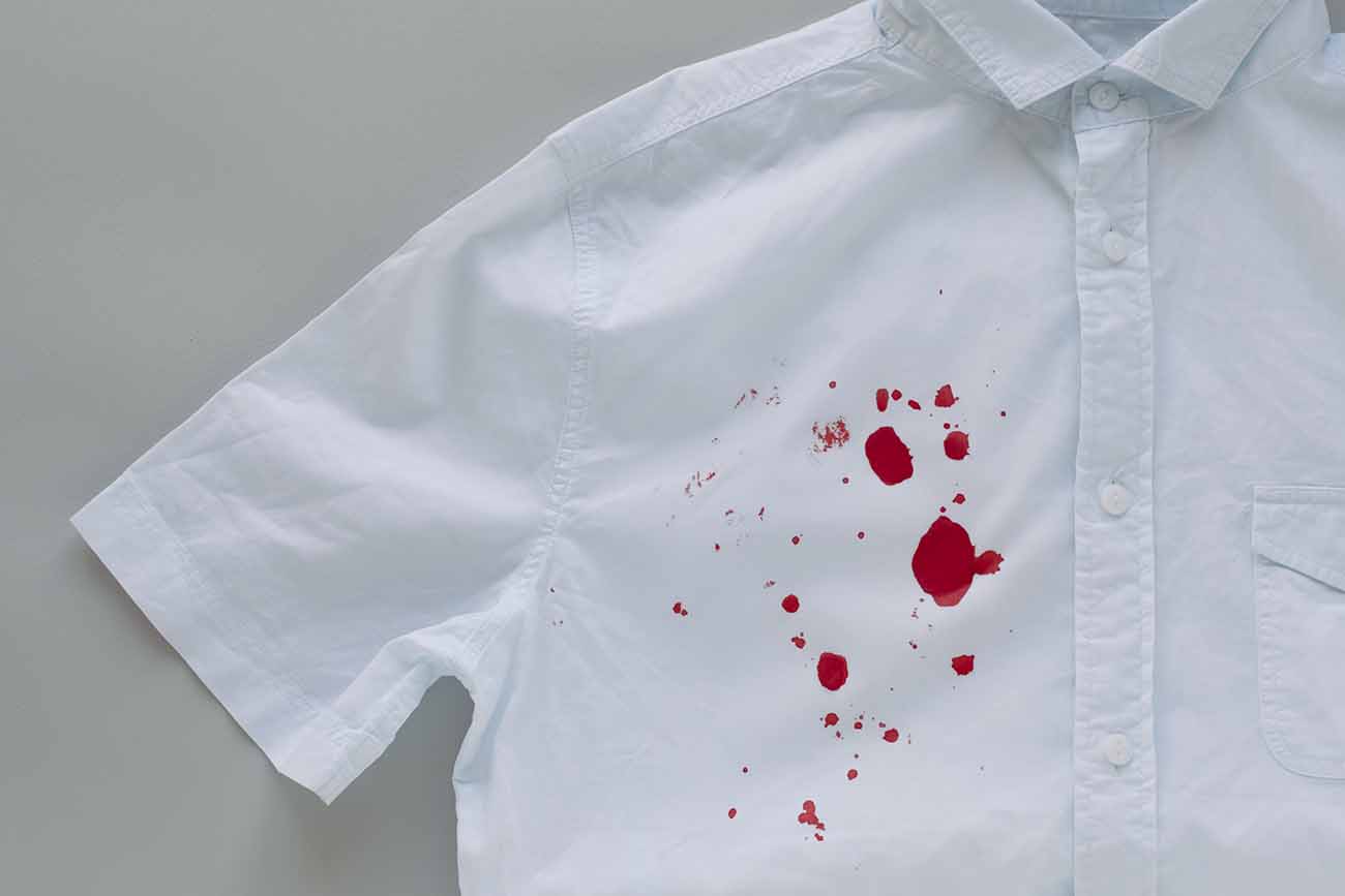 Camisa branca, de manga curta e botões, com pequenas manchas de sangue