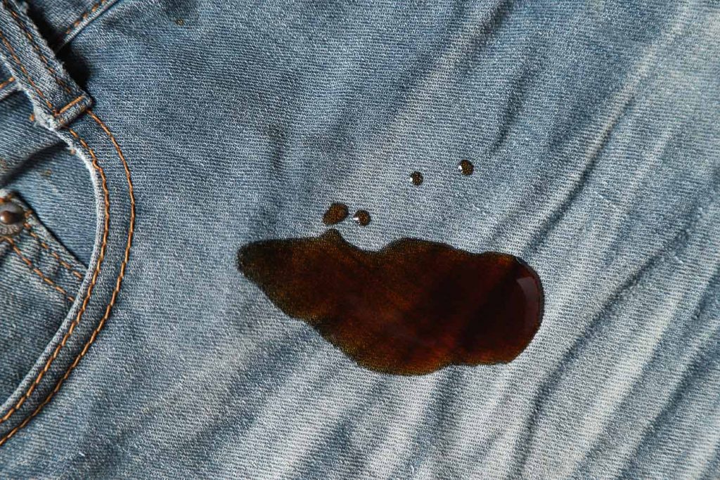 Imagem cortada de uma calça jeans com uma mancha de sangue úmida próximo ao bolso frontal 
